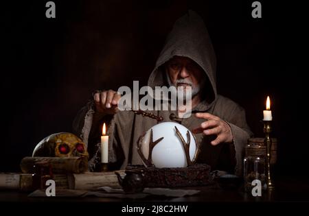 Magician with magic wand on crystal ball with space for product. Stock Photo