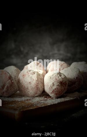 Beef meatball coated in flour on a wooden chopping board.  On a black stone background Stock Photo