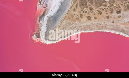 Flying over a pink salt lake. Salt production facilities saline evaporation pond fields in the salty lake. Dunaliella salina impart a red, pink water Stock Photo