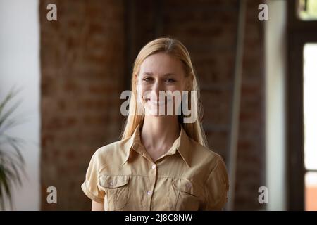 Headshot portrait happy blond woman posing indoor looking at camera Stock Photo