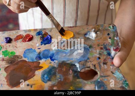 Painter woman holding wooden palette and paintbrush, close up Stock Photo