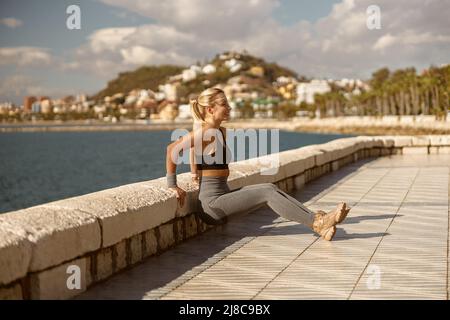 Attractive young woman exercising near beautiful coastline Stock Photo
