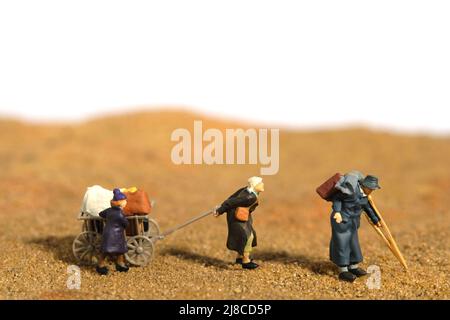 Miniature people toy figure photography. An elder couple with a grandchild refugee walking, moving in the middle of desert, going to refugee camp beca Stock Photo