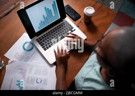 An overhead view of a Black businesswoman analysing reports and graphs Stock Photo