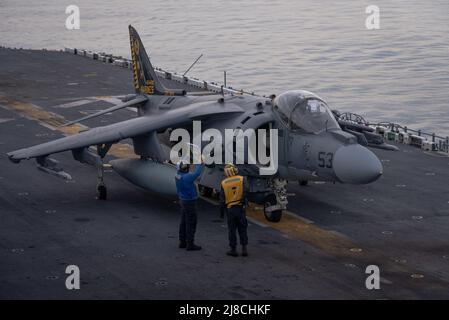 U.S. Navy flight deck crew hold up instructions to a Marine Corps AV-8B Harrier fighter jet attached to the Tigers of Marine Attack Squadron 542, before launch on the flight deck of the Wasp-class amphibious assault ship USS Kearsarge, March 18, 2022 operating on the Atlantic Ocean. Stock Photo