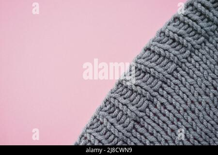 Cozy gray knitted sweater on pink table, copy space. Stock Photo