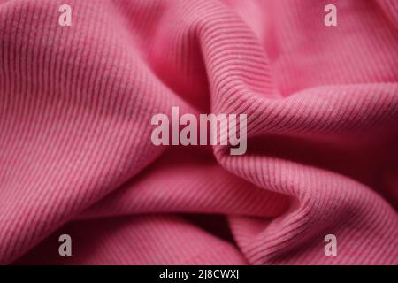 Wrinkled pink micro-ribbed jersey, soft fabric wavy background. Stock Photo