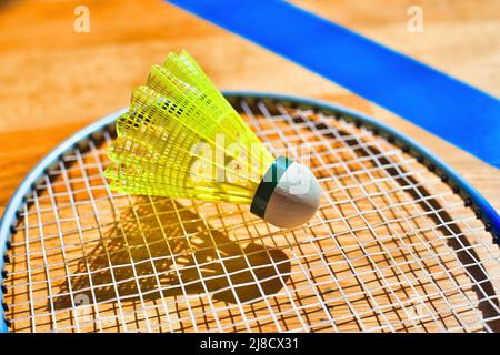 Yellow shuttlecock for badminton lies on strings of racket. Background. Close-up. Stock Photo