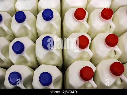 Top view of many plastic jugs of milk with red and blue caps Stock Photo