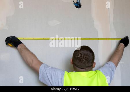 The wizard measures the distance on the wall with a tape measure Stock Photo