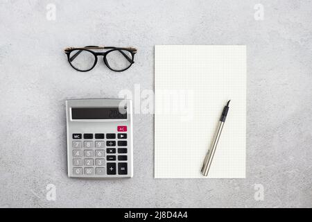 Flat lay paper blank, calculator, pen and eyeglasses on working desk. Background for Data analysis, paperwork, financial research, report. Calculation Stock Photo