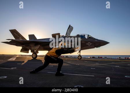 U.S. Navy Aviation Boatswains Mate 1st Class Fidel Colin signals a Marine Corps F-35B Lightning II fighter aircraft, attached to the Flying Lethernecks of Marine Fighter Attack Squadron 122, to launch from the flight deck of the Wasp-class amphibious assault ship USS Makin Island, February 2, 2022 operating on the Pacific Ocean. Stock Photo