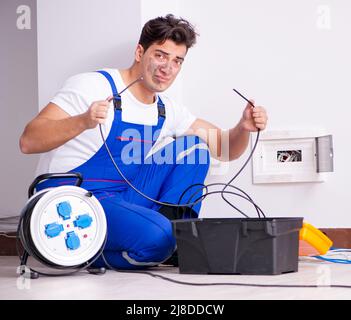 The funny man doing electrical repairs at home Stock Photo