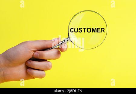 Customer research. Hand with magnifier on yellow background. Analysis and understanding of clients, consumers, their attitudes, needs, behaviors, motivation. Marketing and planning concept. High quality photo Stock Photo