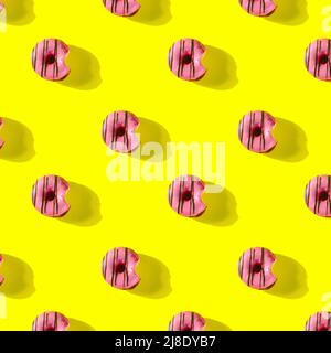 pattern made of Freshly baked donuts  with icing and sprinkles for breakfast on a yellow background . Sweet background. Bakery, baking concept. Stock Photo