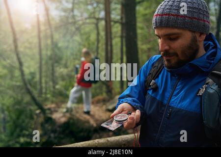 Male tourist using compass for navigation in forest Stock Photo