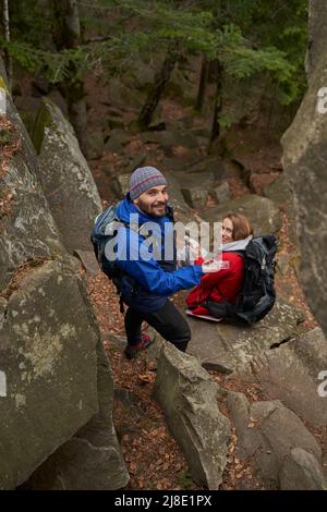Cheerful man using compass during rest stop with woman Stock Photo