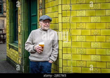 Male stand outside a pub enjoying a drink at The Peveril of the Peak traditional English city pub, located on Great Bridgewater Street, Manchester, UK