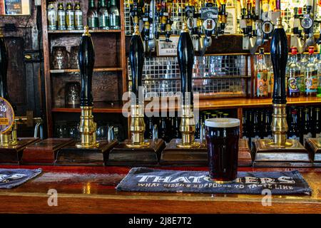 Pint glass of Spingo Ale , on beer mat with bar pumps at The Blue Anchor Inn in Helston, Cornwall , United Kingdom Stock Photo