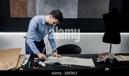tailor make working in atelier. designer near a wooden table with tools for making clothes Stock Photo