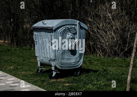 Metallic wheel trash can in park.  Mobile trash can Stock Photo