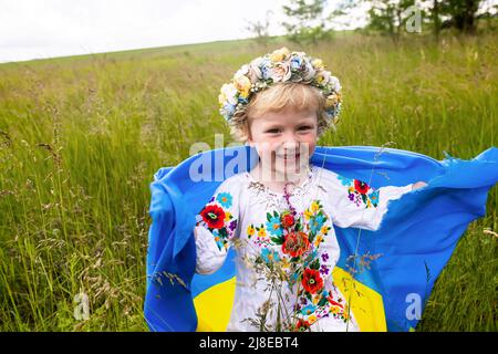 Yellow blue Ukrainian flag in hands of girl running on mangled field of wheat. Happy child with the flag of Ukraine. Independence Day. Flag Day. Const Stock Photo