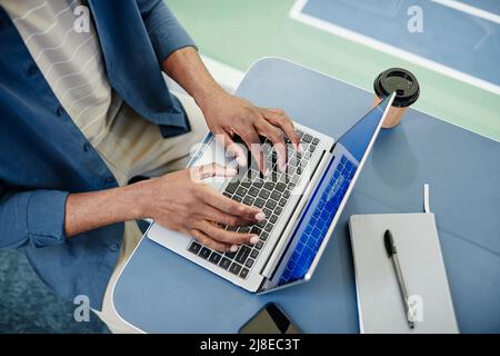 Top view closeup of black man using laptop and typing while working in sports training center Stock Photo