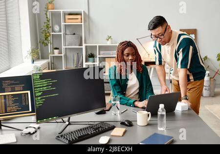 Portrait of two IT developers reviewing code on computer screen in office, female QA engineer at work Stock Photo