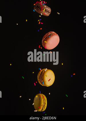 Festive composition. French macarons on a black background with colored confetti in frozen flight. Holiday, birthday, cafe, confectionery. Invitation, Stock Photo