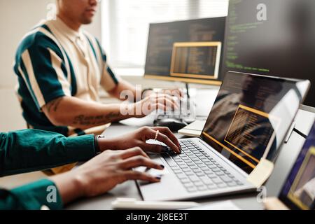 Closeup of two IT developers typing on keyboards while writing code at workplace in office, copy space Stock Photo