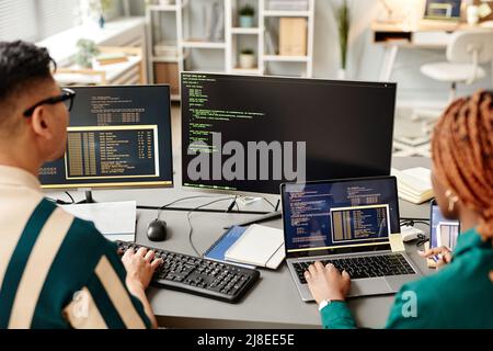 High angle of two IT developers using computers while reviewing code in office Stock Photo