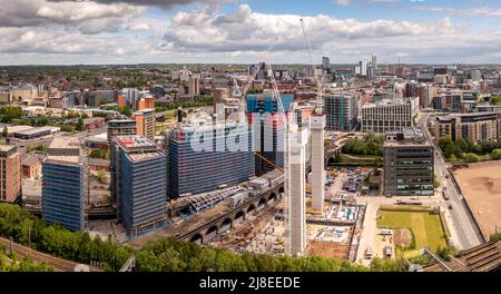 An aerial cityscape view of tall skyscrapers under construction with large cranes lifting building equipment in a Leeds city centre construction site Stock Photo