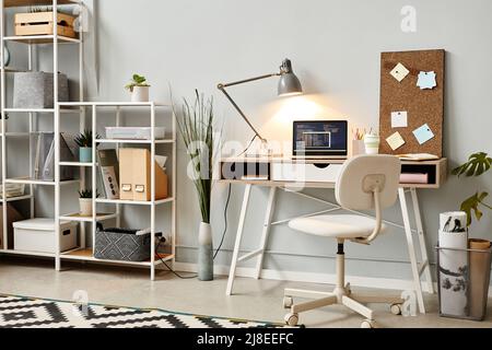 Background image of white home office workplace with code on laptop screen lit by lamplight, copy space Stock Photo