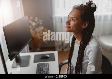 Close up of beautiful young thoughtful woman sitting in room at table looking up Stock Photo