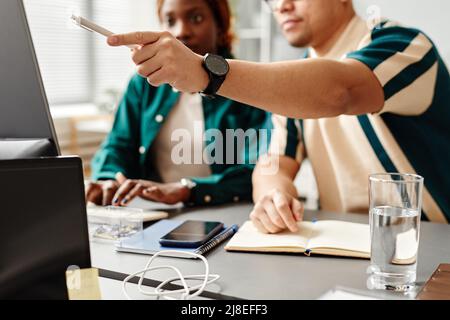Close up of two software developers or QA engineers reviewing code and pointing at computer screen, copy space Stock Photo