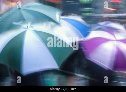 Open colorful umbrellas close up on a rainy day. Street scene. Wet pavement and traffic passing. Unrecognizable people Stock Photo