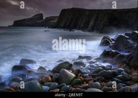 Dark and moody scene with a brooding sky over the stoney beach at North Haven, Fair Isle Stock Photo