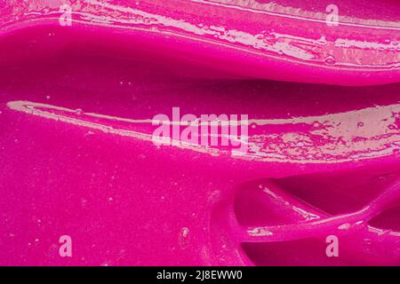 Pink gel texture. Cosmetic clear liquid cream smudge. Skin care product sample closeup. Toothpaste or wax Stock Photo