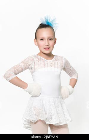 Portrait of caucasian girl ballerina nine-year-old in white ballet tutu skirt, blue bow in hair and white mittens on white background. Waist up Stock Photo