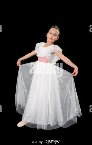 Girl ballerina in white long dress dancing on black background. Full length, studio shot. Caucasian ballet dancer nine-year-old. Part of photo series Stock Photo
