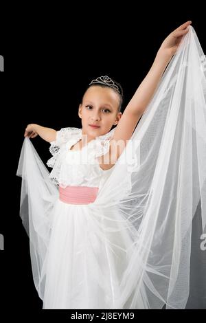 Girl ballerina with diadem on head dressed in white long dress theatrical dancing on black background. Part of photo series Stock Photo