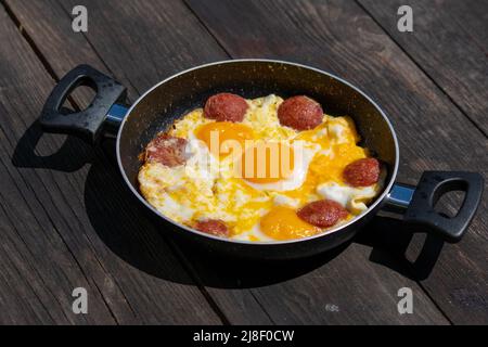 Selective focus closeup shot of fried eggs in frying pan on wooden table. Stock Photo