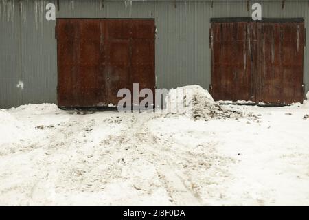 Garage door in winter. Entrance to warehouse. Production room. Rusty doors. Stock Photo