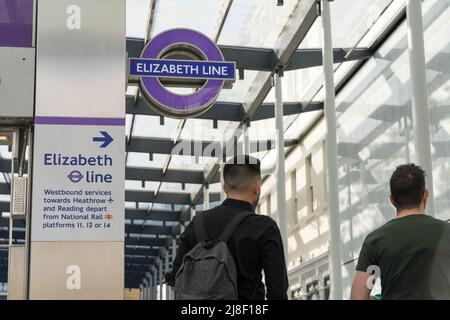two passengers walk past an ELIZABETH LINE logo, new crossrail train line (purple line), Paddington station London England UK Stock Photo