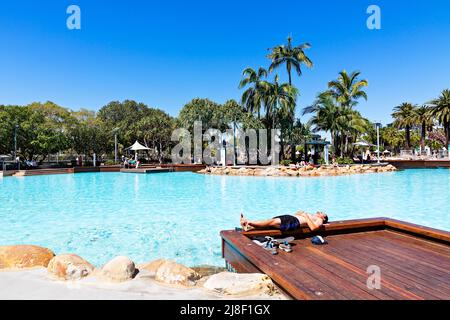 Brisbane Australia / A young man enjoys the sunshine at Streets Beach an urban man made swimming beach. Stock Photo