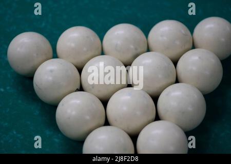 Billiard balls are collected in triangle. White balls on pool table. Details of sports equipment. Green cloth on table. Preparation of game. Stock Photo