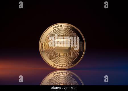 Solana SOL Cryptocurrency Physical coin placed on reflective surface and lit with Purple and Red lights. Macro Shot. Stock Photo