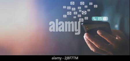 Hand holding using mobile phone with email icon on screen. Business communication technology concept. Hand man holds phone sent and receive email from Stock Photo