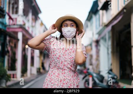 Travelers with mask walking on street Phuket old town with Building Sino Portuguese architecture at Phuket Old Town area Phuket, Thailand. Travel conc Stock Photo