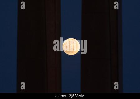 Malaga, Spain. 15th May, 2022. The full moon, known as the 'blood red moon' is seen rising behind two columns before a total lunar eclipse. On the night of 16 May, a total lunar eclipse will appear in the night skies and will be visible in Europe. During the total lunar eclipse, the light of the moon reflects a red and orange light. (Photo by Jesus Merida/SOPA Images/Sipa USA) Credit: Sipa USA/Alamy Live News Stock Photo